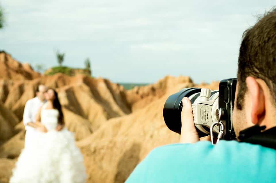 תמונה של צלם מיוחד שמצלם מגנטים לאירועים בבאר שבע רואים צלם עם מצלמה ומאחורה ברקע יש זוג מתחתן 